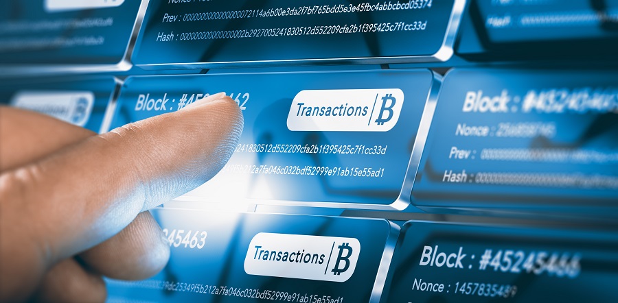 Finger pressing a blockchain block with the text transaction, a bitcoin symbol and security sha256 algorithm hach. Composite between a hand photography and a 3D background
