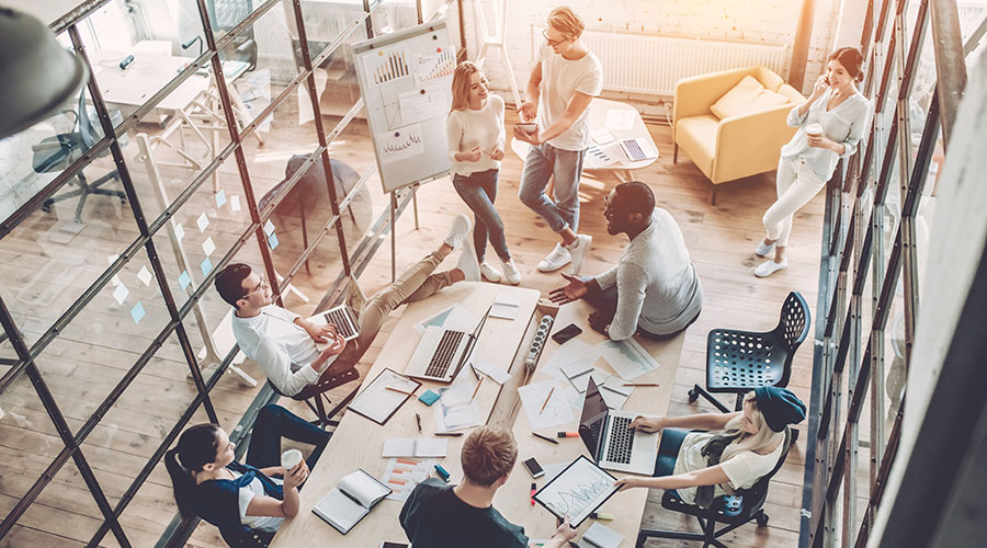 Top view of multiracial young creative people in modern office. Group of young business people are working together with laptop, tablet, smart phone, notebook. Successful hipster team in coworking. Freelancers.