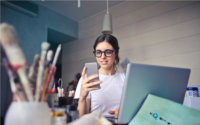 woman looking at phone sitting at art desk