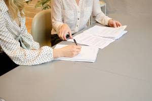 Businesswomen discussing merger and acquisition with paperwork