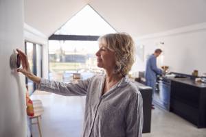woman adjusting temperature on smart thermostat