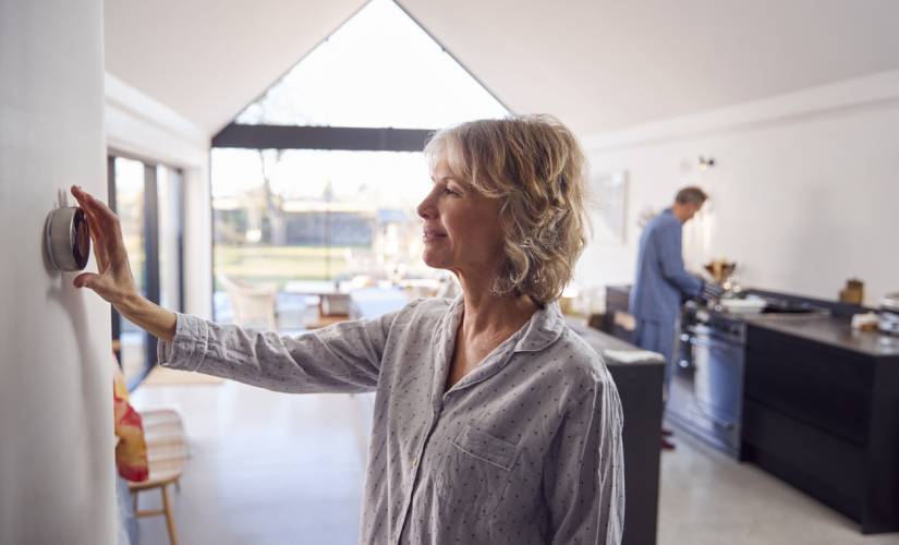 woman adjusting temperature on smart thermostat