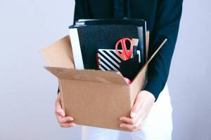 A photo of a person carrying a box of office items