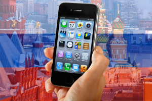 Apple pays $13.7m fine to Russia in antitrust lawsuit. iPhone held up in front of transparent Russian flag and Kremlin building