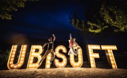 A phot showing two people leaping into the air in front of a lit Ubisoft sign.
