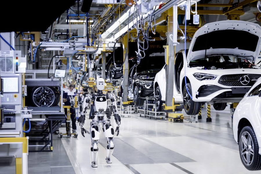 Apollo robot stood alongside Mercedes-Benz production line. Cars are lined up