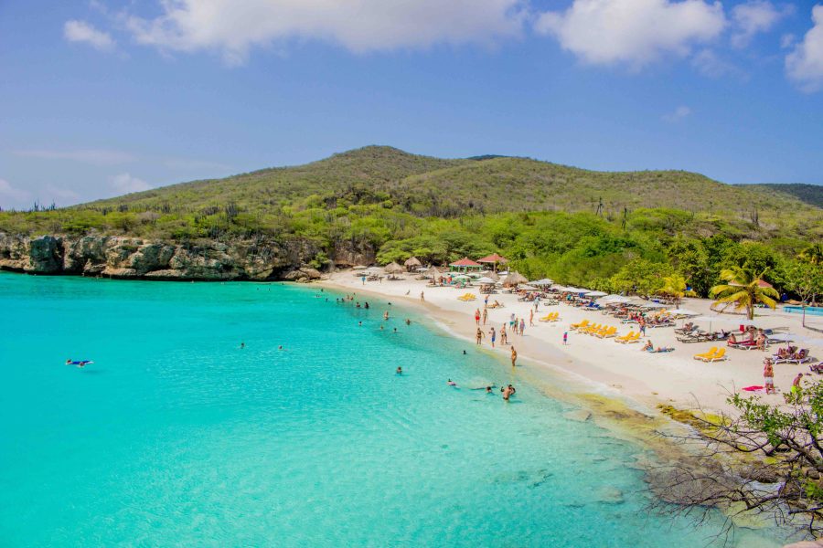 Beach on Grove Knip, Curaçao. Blue waters with sandy white beach and people sunbathing and swimming in the sea