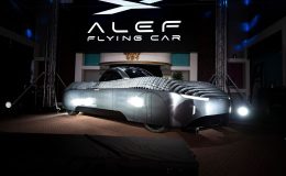 Alef Aeronatic's 'flying car' displayed in a showroom. The car has a white and grey chasis and a black screened central cabin for passengers