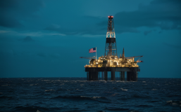 a lone oil rig at night on a dark choppy sea with an American flag coming out of it, cinematic.