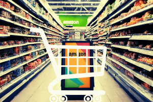 Amazon scraps Just Walk Out to smart carts in Fresh stores. White graphic of shopping cart in front of Amazon sign in the middle of a supermarket aisle