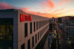 Netflix sign on a building at sunset. Can see the traffic in the background next to the building.