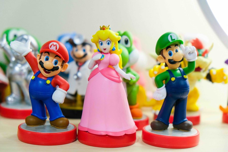 Nintendo amiibo toys of characters Mario, Luigi, and Peach stood next to each other. Figurines.