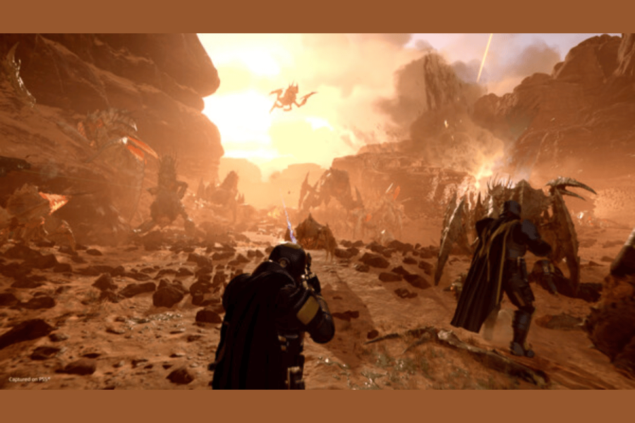 Sony reverses PSN requirement, yet bars Helldivers 2 sales in over 170 countries. This image depicts an intense battle scene from a video game, set in a rocky, desert-like environment under a hazy, orange sky. In the foreground, a player character in a black cloak and helmet aims a futuristic weapon at distant enemies. These enemies include various large, insect-like creatures and a flying beast. The scene captures a moment of dynamic combat, emphasizing a sci-fi theme with its otherworldly setting and creatures.