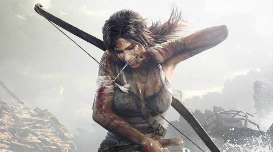Lara Croft, the eponymous tomb raider, is kneeling in the middle of the frame. her arm is wounded and she is using her teeth to tear off a bandage around it.