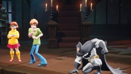 Velma and Shaggy from Scooby Doo stand at left as Batman appears in a combative crouch in Warner Bros.' games weird platform-fighter MultiVersus
