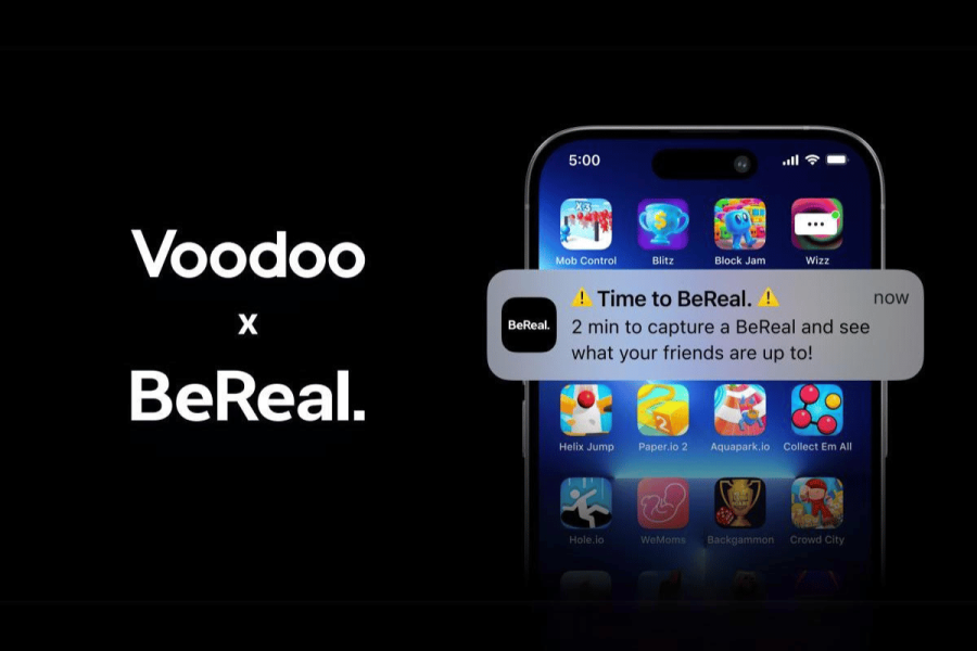 Voodoo acquires BeReal for €500M as app's popularity declines. This image shows a mobile phone screen displaying a collaboration between Voodoo and BeReal, indicated by the text "Voodoo x BeReal." The phone screen shows a notification from the BeReal app, which reads, "Time to BeReal. 2 min to capture a BeReal and see what your friends are up to!" This notification is part of the user interface that includes various game icons from Voodoo, suggesting a potential integration or collaboration between the gaming company Voodoo and the social media app BeReal. The background is dark, focusing attention on the brightly colored app icons and the notification.