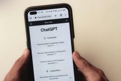 Close up of man holding a phone with the ChatGPT mobile interface on it