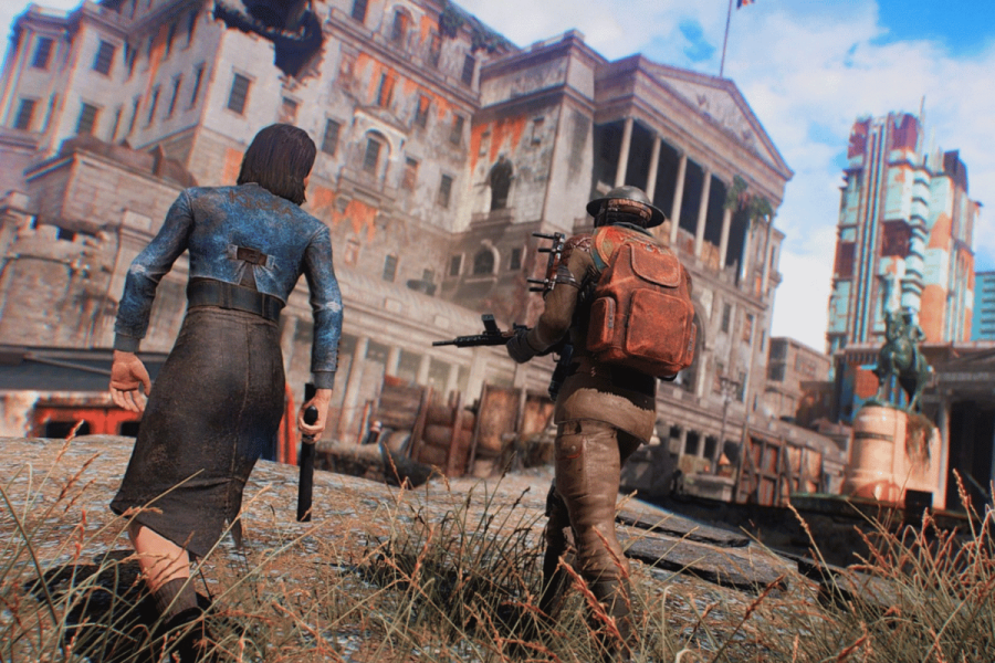 Fallout: London developers announce fixes after troubled launch. The image depicts two characters in a post-apocalyptic video game setting. The character in the foreground, a woman with short dark hair, wears a tattered blue top and a long skirt, holding a knife in her right hand. Her posture suggests readiness or tension. The character in the background, a man equipped with a large backpack and a rifle, is dressed in worn clothing suitable for survival. They are in an urban environment with dilapidated buildings and a faded statue, giving the scene a desolate and abandoned atmosphere. The architecture and aesthetic hint at a setting that mixes historical and futuristic elements.
