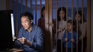 An image of a family shut behind a gate while the father plays games because of no family pass