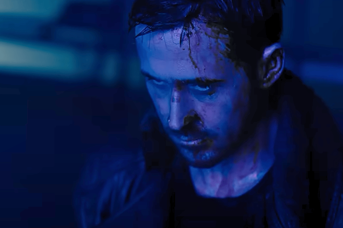 Ryan Gosling stars in Blade Runner 2049, depicted in a dark scene with blue hues.