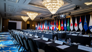 Room with long table, covered in black tablecloth. Numerous flags are on the table representing a number of different countries.