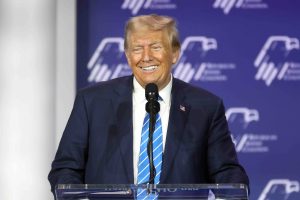 Former President of the United States Donald Trump speaking with attendees at the Republican Jewish Coalition's 2023 Annual Leadership Summit at the Venetian Convention & Expo Center in Las Vegas, Nevada. He's stood on stage, behind a podium. It's a close up image showing just his torso and face.