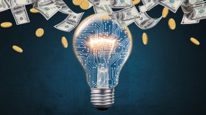 An abstract image of a light bulb with a circuit board pattern. The light bulb is glowing brightly. There are dollar bills and coins falling from the light bulb. The background is a dark blue.