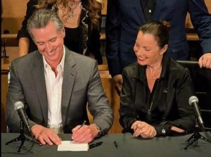 Gov. Newsom Signs Union-Championed A.I. Bills at SAG-AFTRA Plaza with SAG-AFTRA there in person. Group of three people stood arournd Governor signing bill into law.