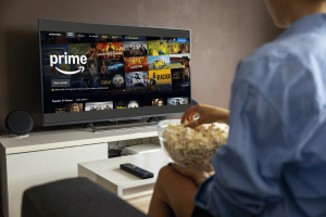 BBC and other UK broadcasters unite for new Amazon streaming deal with Freely. Person with popcorn watches Amazon Prime on TV