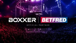 Boxxer logo on the left, Betfred on the right and in the middle of the screen. It sits on a background image of a boxing event.