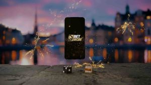 Phone in the centre, with BetMGM logo on it. Two dice are in front and it's on a cityscape backdrop.