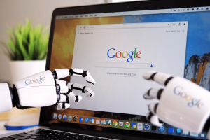 Robot hands reaching out of Google browser on laptop with Google logos on hands. Google's Project Jarvis AI aims to automate tasks using your web browser - report