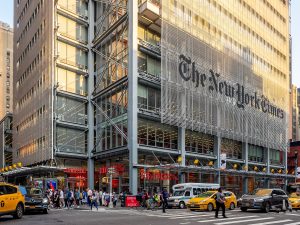 New York Times building in Midtown Manhattan, NYC. Traffic and yellow cabs in front of the building.