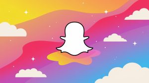 An illustration of the Snapchat logo on a dynamic background. The background is a gradient of pink and purple with a few white clouds scattered throughout. There are also some stars in the sky. The Snapchat logo is white and is placed on a pink cloud. The overall image has a soft, dreamy atmosphere.