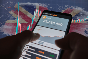 Robinhood CEO Vlad Tenev criticizes 'backwards' UK crypto policy amid gambling concerns. Smartphone displaying a cryptocurrency wallet with Bitcoin value and a price chart, set against a backdrop of the United Kingdom flag and stock market graphs.