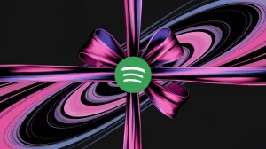 A digital illustration of a Spotify logo wrapped up in a bow. The background is a dynamic, abstract design of pink, purple, and blue swirls. The overall image has a festive feel.