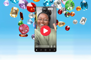 YouTube introduces Jewels and gifts to support creators during live streams. A smartphone screen shows a woman smiling during a live stream, with a large play button overlaid in the center. Surrounding the phone are colorful animated jewels in various shapes and colors, including red, green, blue, yellow, and purple, set against a gradient blue background. The screen features live streaming icons and a "Subscribe" button at the top, representing YouTube's new Jewels and Gifts feature for supporting creators during live streams.