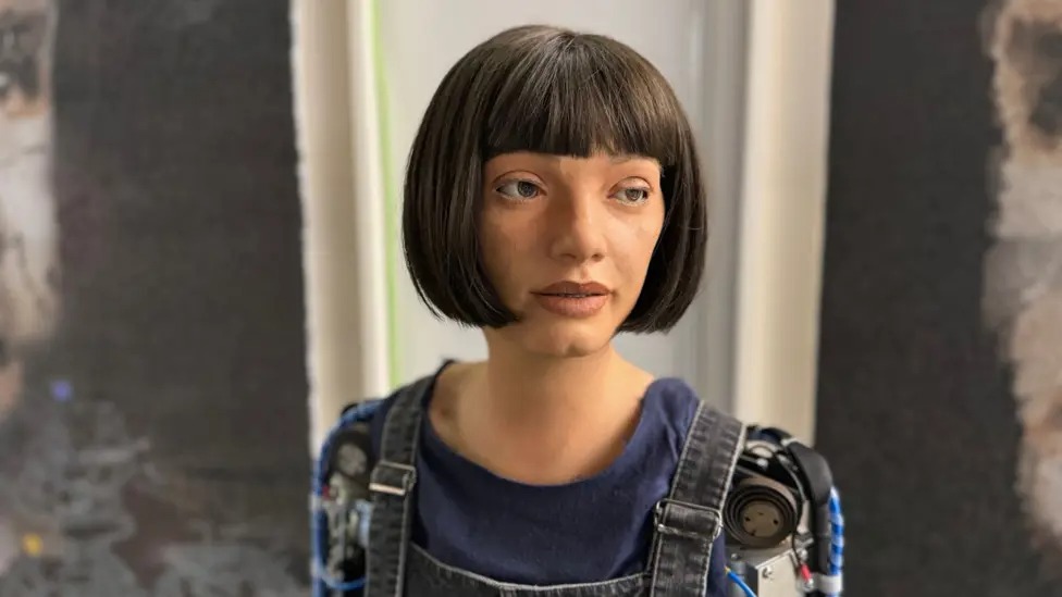 Ai-Da the AI artist is a humanoid woman with a black bob and a robot arm.