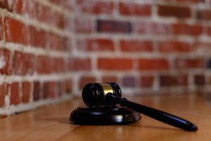 Wooden gavel laid on a wooden desk, with brick wall in the background.