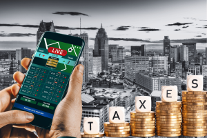 Michigan proposes tax hikes for sports betting and igaming operators. A person holding a smartphone displaying a live sports betting app with a cityscape of Detroit in the background and stacks of coins spelling 'TAXES' in the foreground.