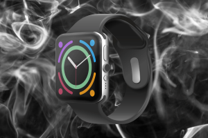 Apple sued over alleged PFAS 'forever chemicals' level in watch bands. A smartwatch with a black band displayed against a smoky, dark background. The watch screen shows colorful activity rings and a clock face.