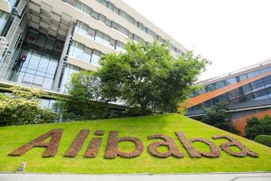 Alibaba logo written into grass with two buildings sat behind it.