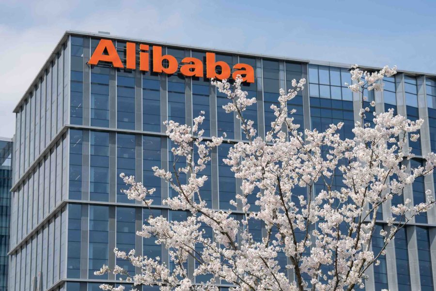 Office building with Alibaba logo in orange at the top. There's a tree in front of it.