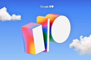 Google IO 2025 when it is and what we can expect. Google I/O 2025 event artwork featuring a blue sky background with white clouds. The 'I/O' logo is depicted as three-dimensional geometric shapes with a vibrant rainbow gradient. The Google logo is positioned above the event branding.