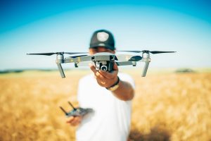 Drone in a field of crops being held by a drone pilot.