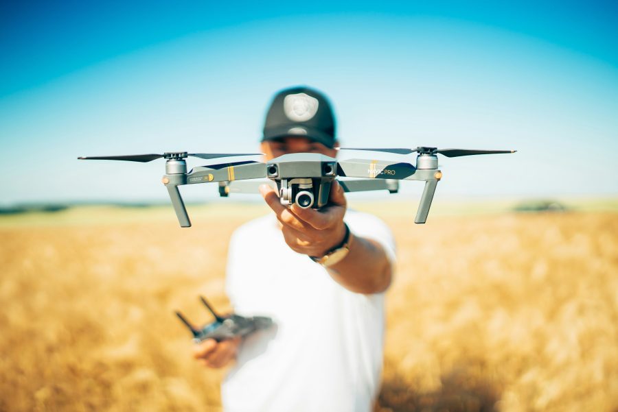 Drone in a field of crops being held by a drone pilot.