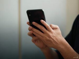 Person's hands close up of them holding a black smartphone.