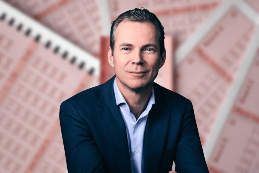 Dutch Lottery sues Lalabet as it seeks millions over illegal gambling in Netherlands. CEO Arjan Blok wears dark suit and blue shirt in front of blurred image of lottery tickets.