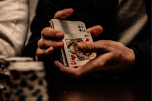 NSW police crack down on illegal casinos as Sydney's underground gambling grows. Person holding deck of cards and blurred image of chips