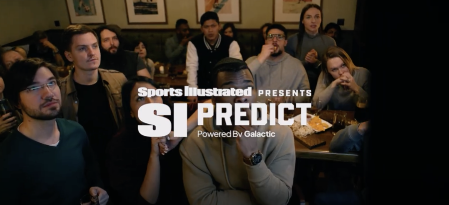 Group of people stood around watching a TV, Sports Illustrated logo is in the center.